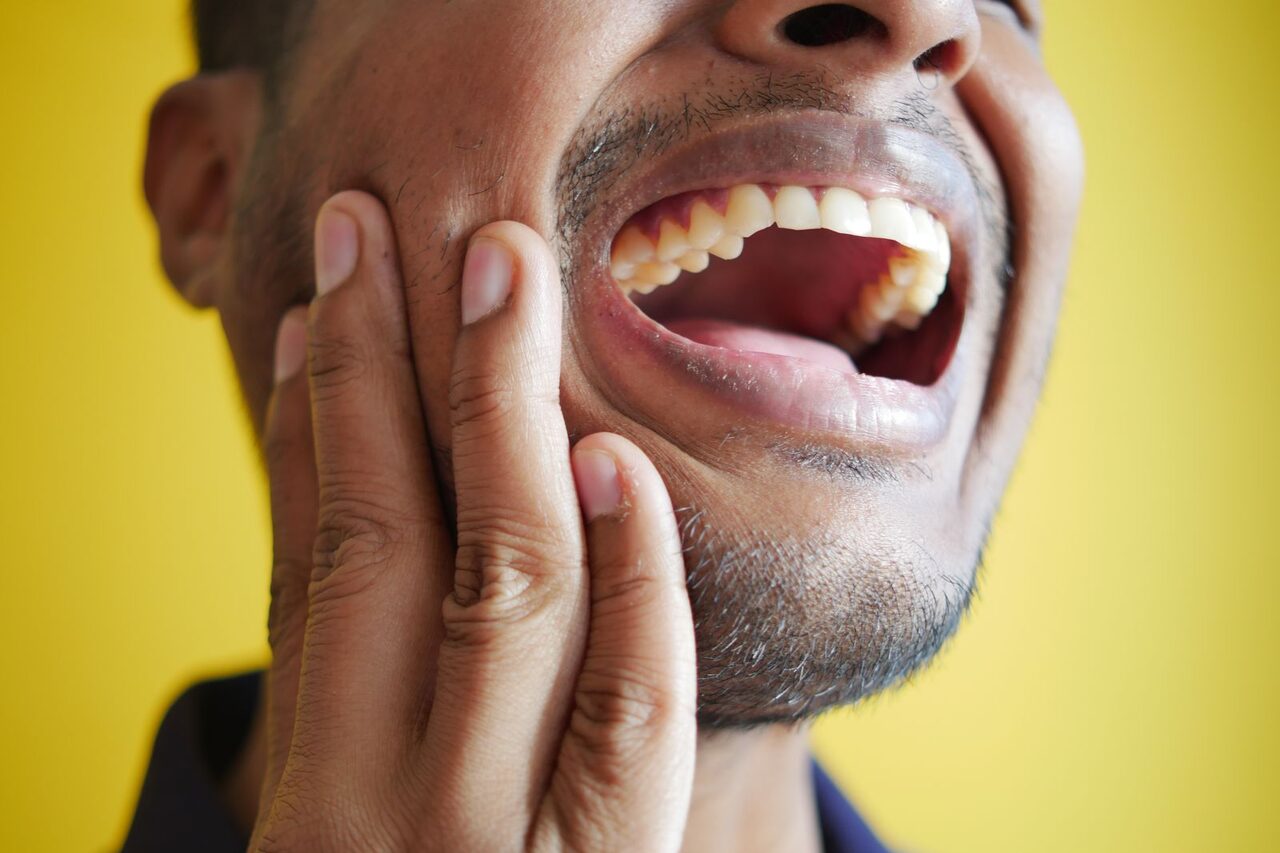En esta fotografía, vemos a un hombre sufriendo un intenso dolor de mandíbula